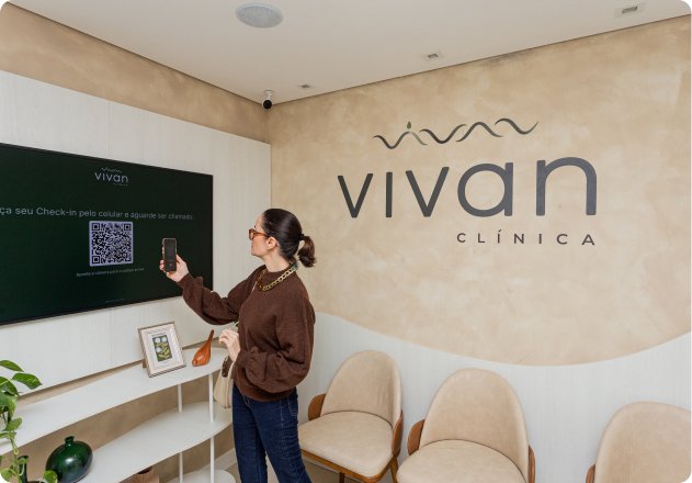 Profissional fazendo check-in por QR Code na TV da recepção da Vivan